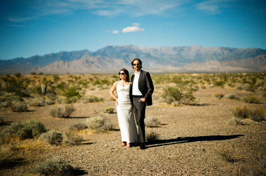 Dreamy 35mm analogue wedding portrait of a couple standing in the Nevada desert with mountains in the background during an elopement.