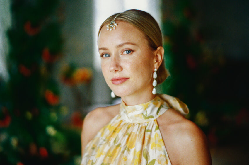35mm film portrait of a bride in a yellow floral dress, pearl earrings and forehead jewellery during her haldi celebration.